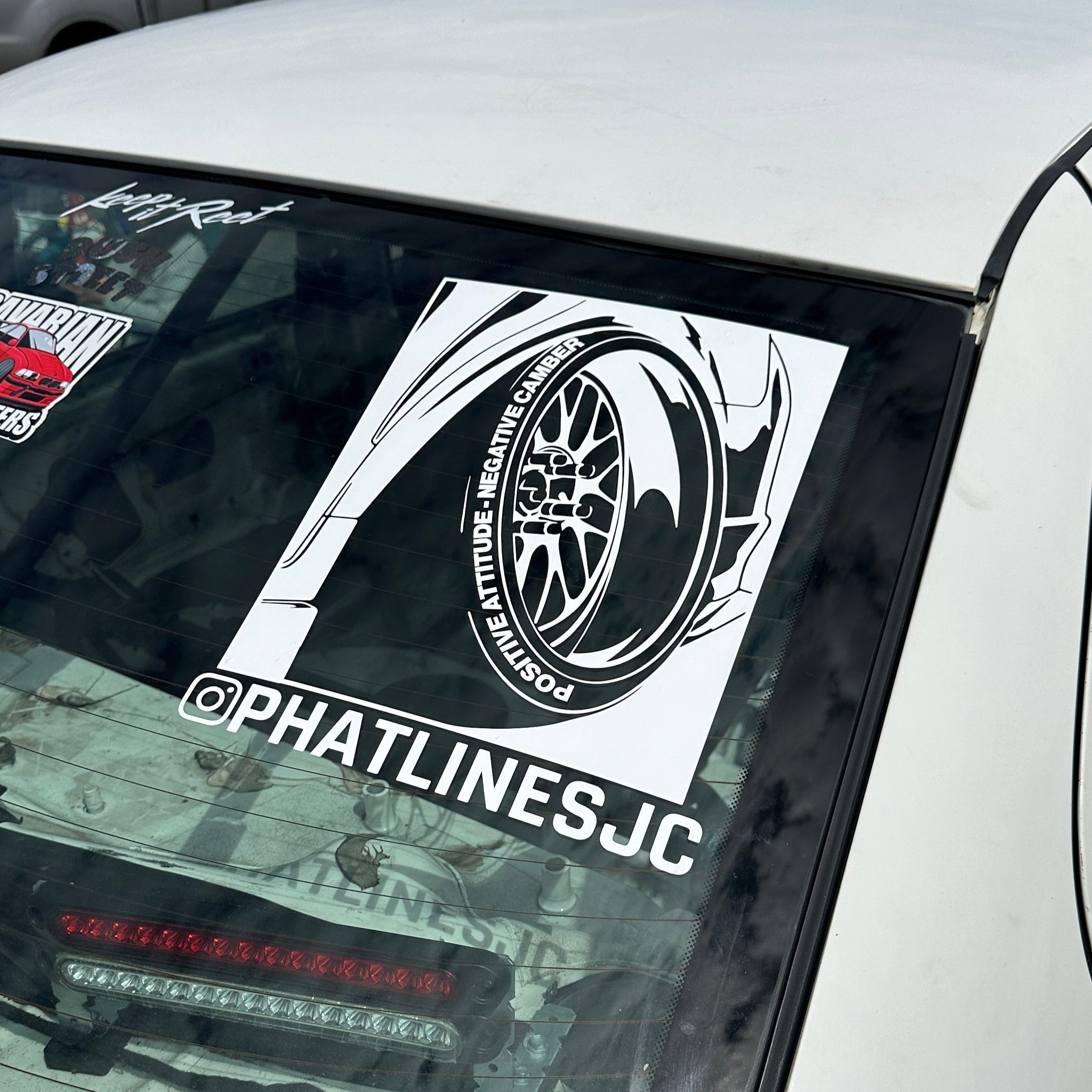 Car window with a sticker featuring a tire graphic and 'PHATLINESJC' branding.